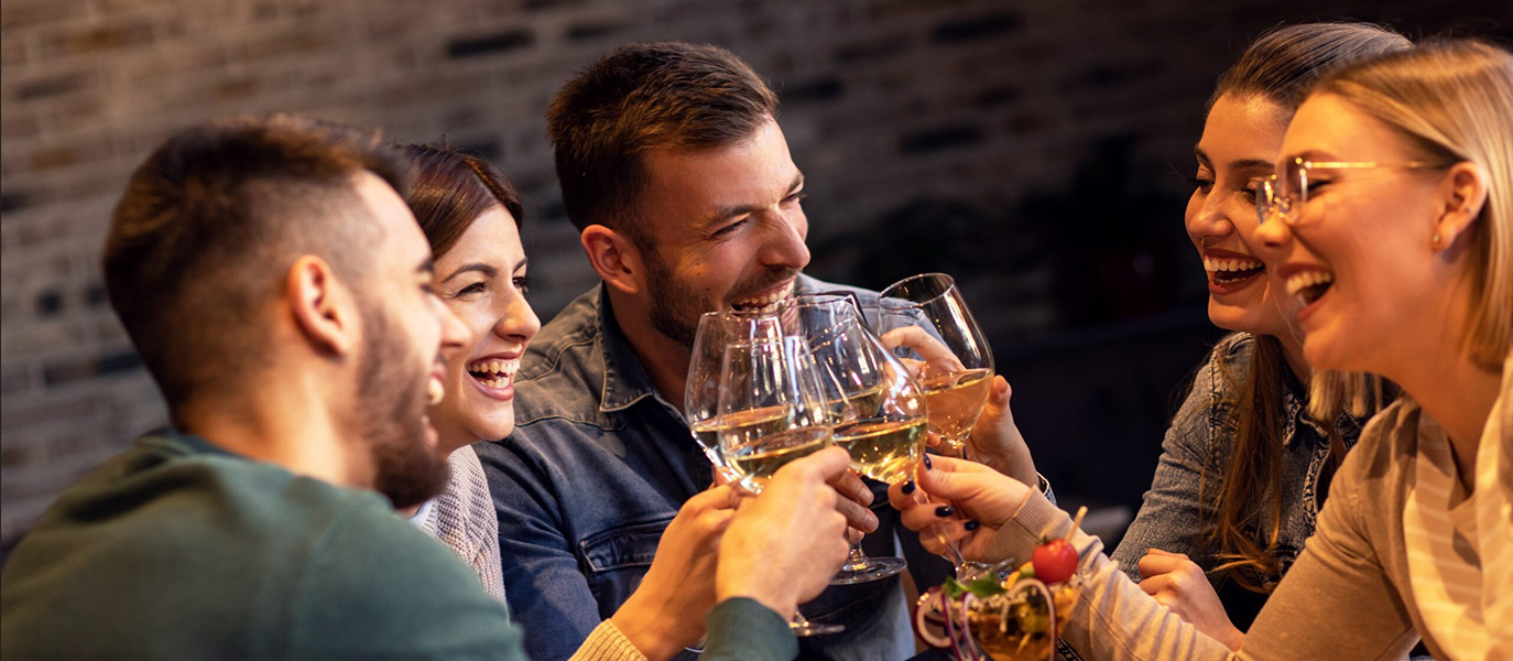 Eine Gruppe Frauen und Männer stossen mit einem Glas Wein an