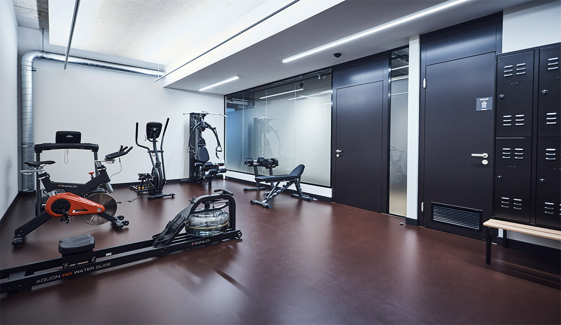 L'espace fitness du Westhive Zurich Stettbach Mitte, équipé d'appareils de musculation, de casiers et d'une douche