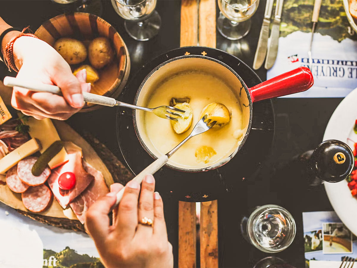 Reich gedeckter Tisch mit einem Fondue-Caquelon aus der Vogelperspektive