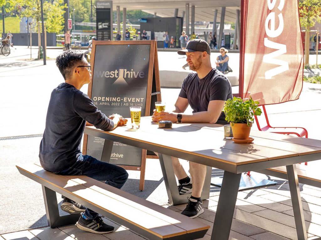 Zwei Männer sitzen im Aussenbereich der Westhive Kitchen Stettbach